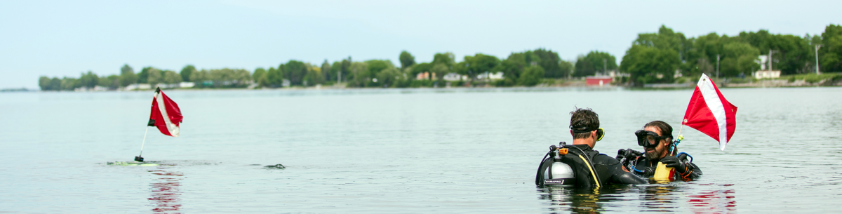 Divers emerging from water at Cape Vincent with diver warning buoy in background